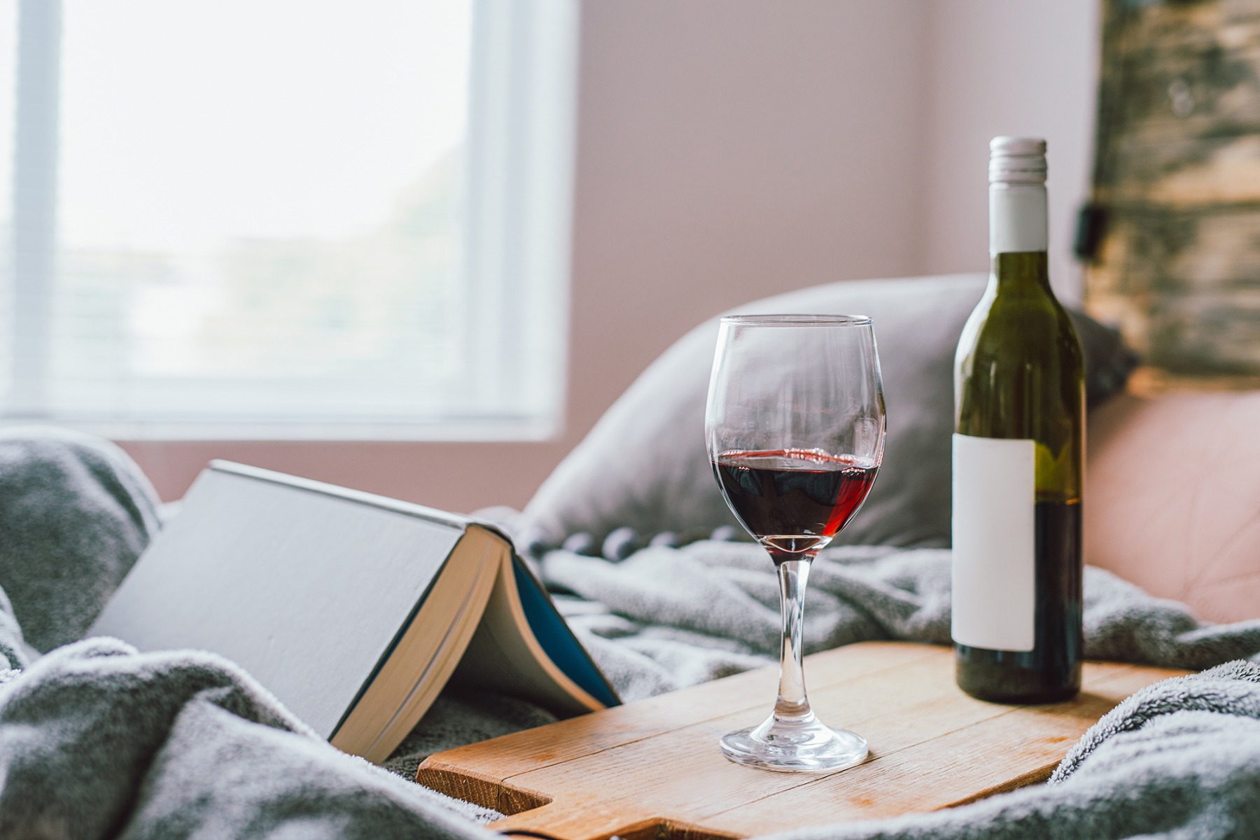 Red wine glass and wine bottle next to a book